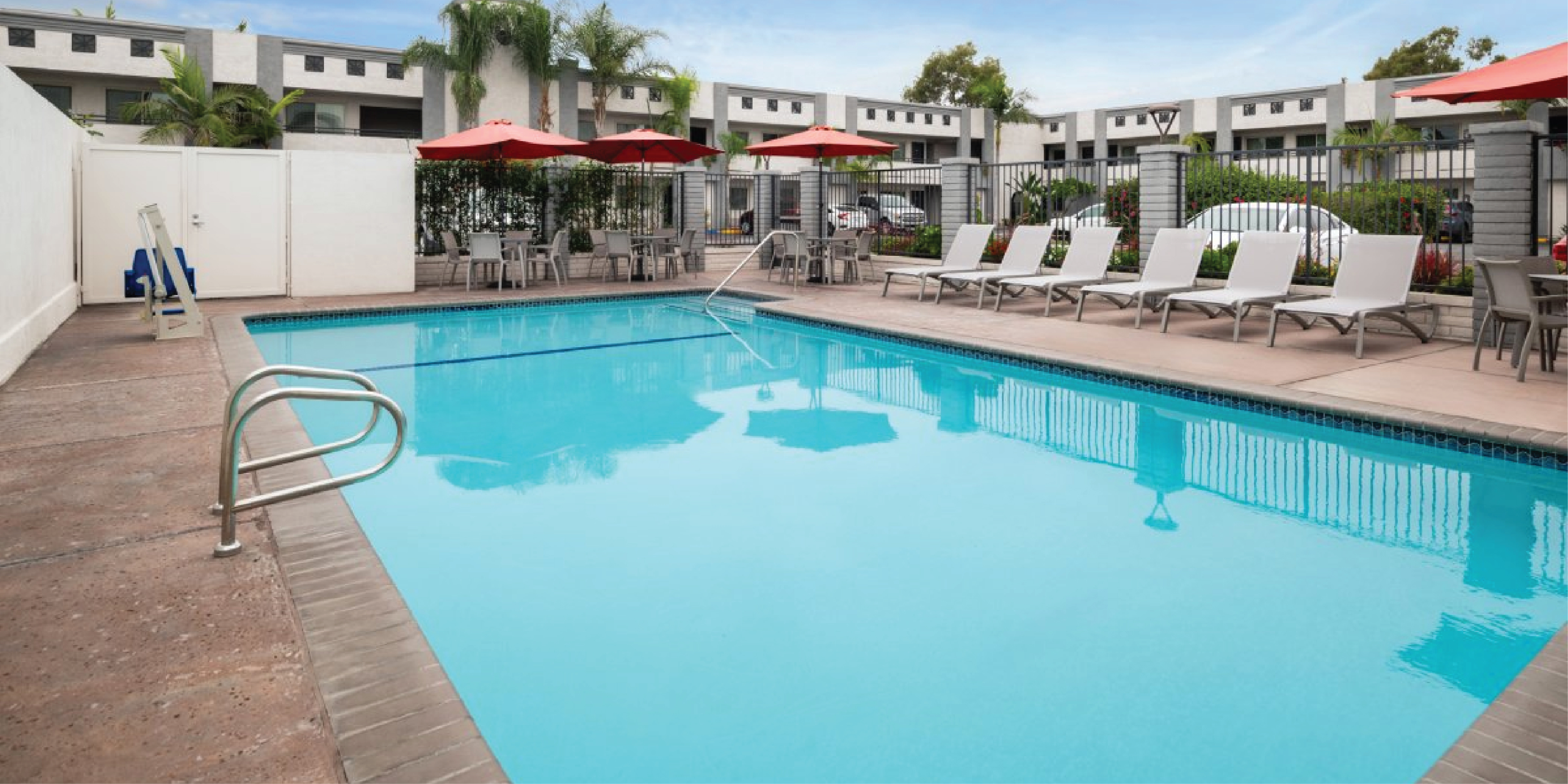 A pool with lounge chairs and umbrellas in front of a building